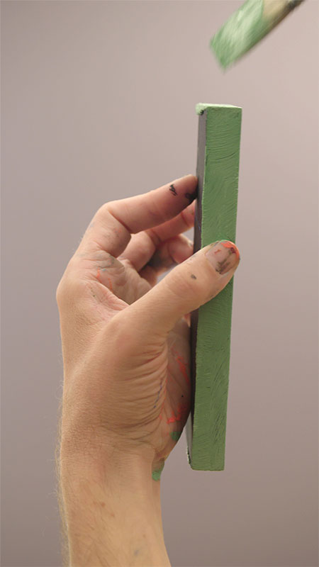 Een houten blokje met groene verf en een kwast